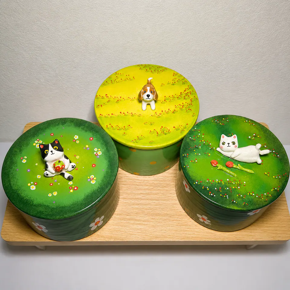 Three green personalized ceramic urns with hand-modeled cat and dog portraits